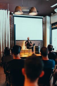 Photo Of Man Sitting In Front of Audience 